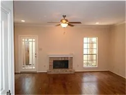 an empty room with wooden floor chandelier fan and windows