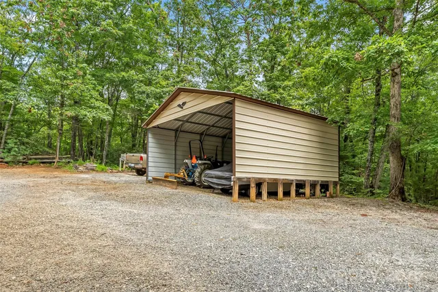 a view of a house with large trees and sitting area in front of house