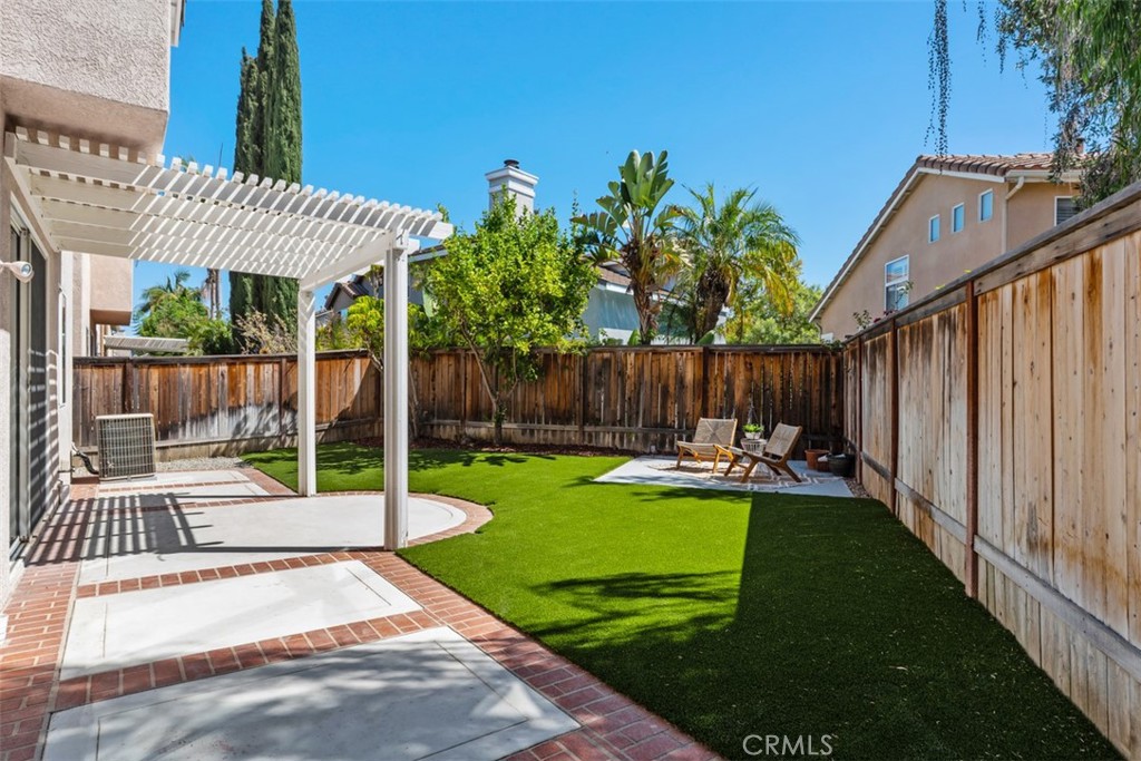 56 Acorn Ridge Rancho Santa Margarita, CA 92688 - Photo 39 of 57 Backyard / Patio: Covered patio with pergola-style shade, brick-accented hardscape, and a turf lawn creates a versatile outdoor entertaining space.