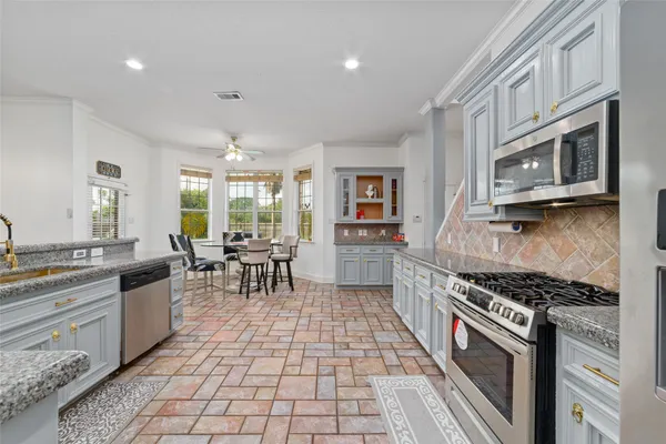 a kitchen with stainless steel appliances granite countertop a stove a sink and a microwave
