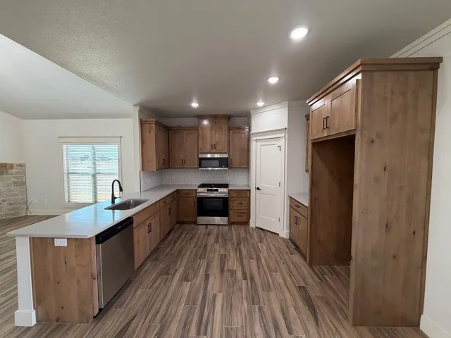 a large kitchen with a center island wooden floor stainless steel appliances and windows