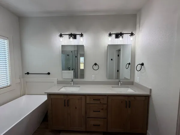 a bathroom with a double vanity sink mirror and bathtub