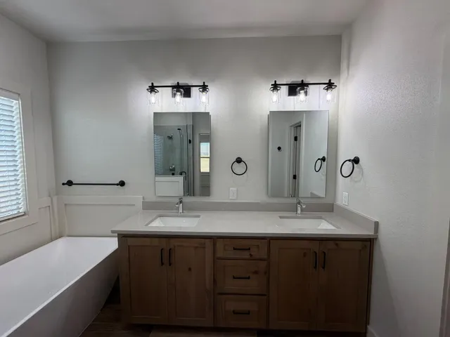 a bathroom with a double vanity sink mirror and bathtub