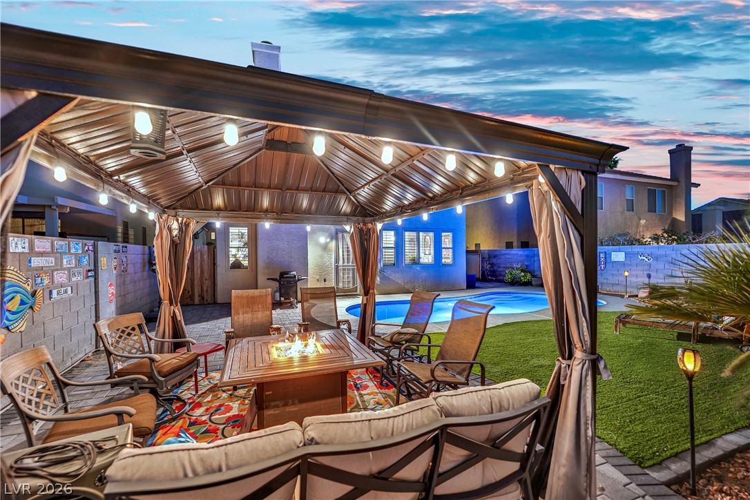 1724 Millstream Way Henderson, NV 89074 - Photo 48 of 60 An inviting backyard oasis features a covered patio with a fire pit, overlooking a private swimming pool.