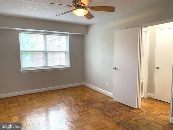 a view of an empty room with window and chandelier fan