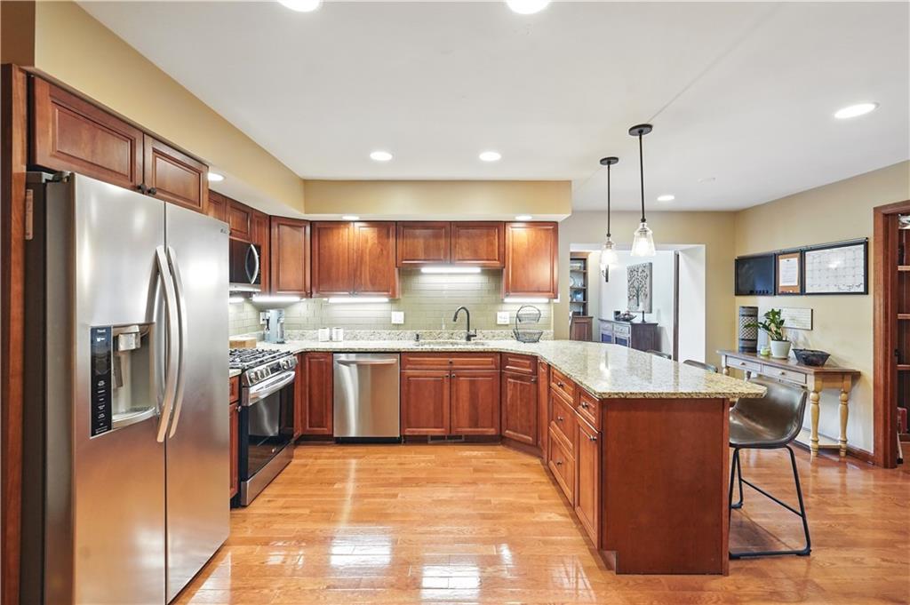 1751 Hassam Road Coraopolis, PA 15108 - Photo 12 of 50 a open kitchen with stainless steel appliances granite countertop a refrigerator a sink dishwasher a stove and white cabinets with wooden floor