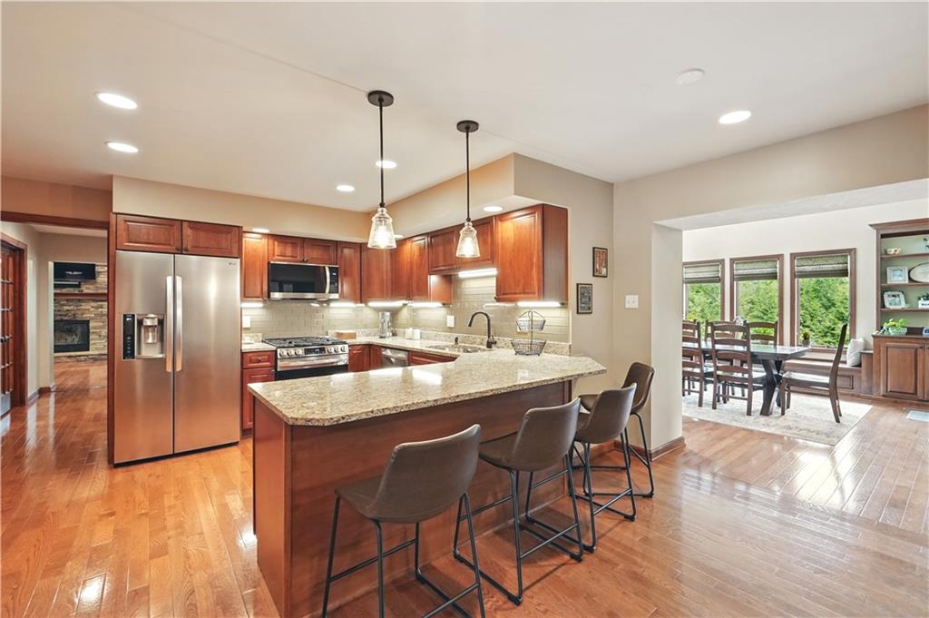 1751 Hassam Road Coraopolis, PA 15108 - Photo 13 of 50 a kitchen with stainless steel appliances granite countertop a stove a refrigerator a kitchen island a dining table and chairs with wooden floor