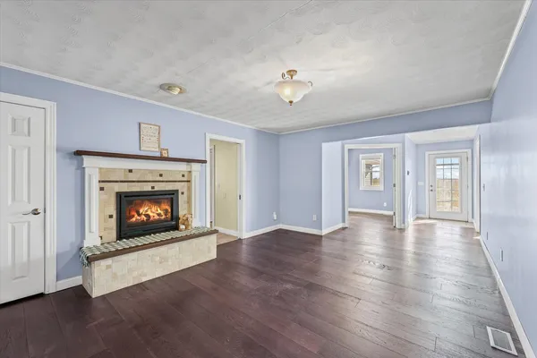 a view of an empty room with wooden floor fireplace and a window