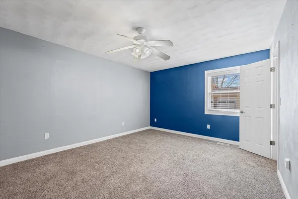 a view of an empty room with chandelier fan and fire place