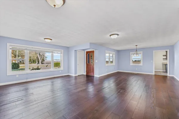 a view of an empty room with window and wooden floor