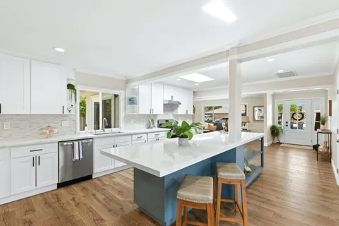 a kitchen with a dining table chairs wooden floor and appliances