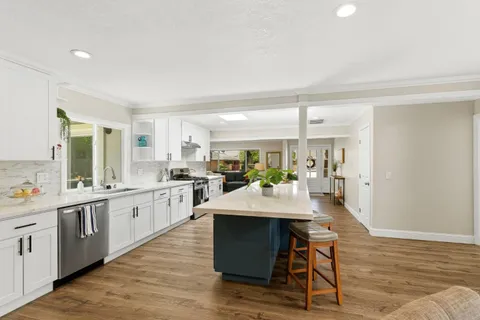 a room with stainless steel appliances kitchen island granite countertop a table chairs and a refrigerator