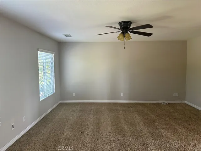 an empty room with windows and fan