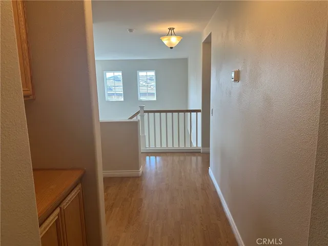 a view of a hallway with wooden floor and a bathroom