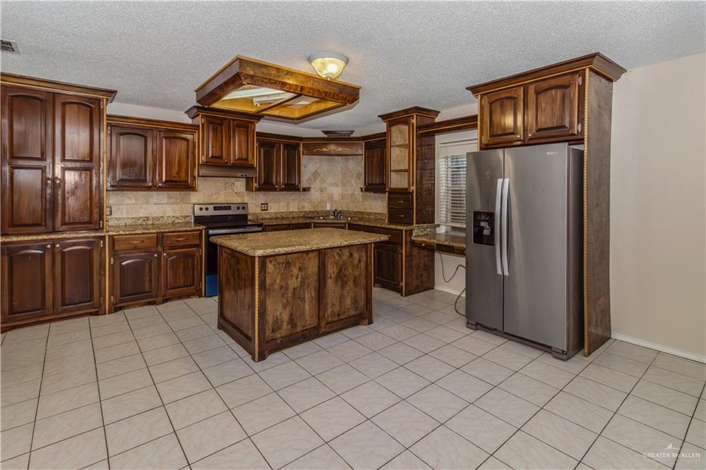 207 East Saenz Avenue Pharr, TX 78577 - Photo 14 of 21 a kitchen with stainless steel appliances granite countertop a stove top oven a refrigerator and cabinets