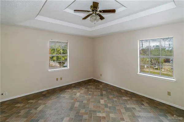 an empty room with windows and ceiling fan