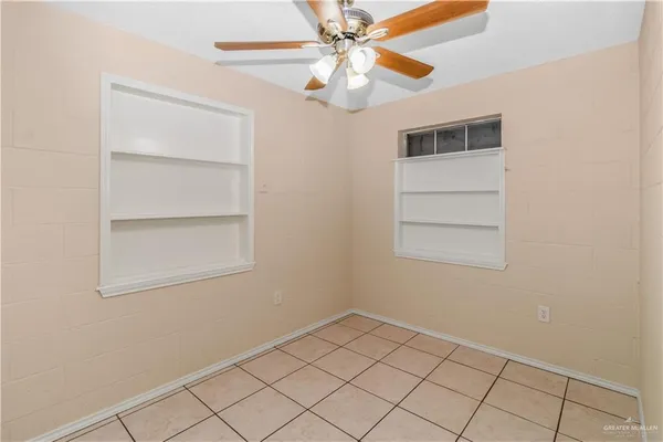 an empty room with windows and fan