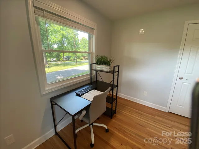 a view of a workspace with furniture and a window