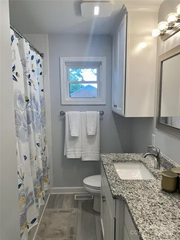 a bathroom with a granite countertop sink toilet and shower