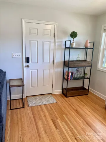 a view of an empty room with window and hardwood floor