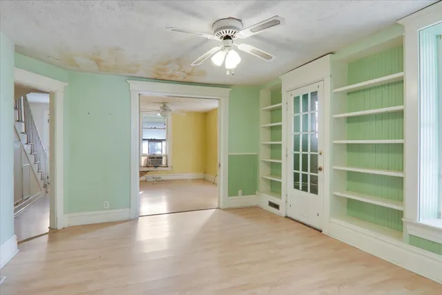 a view of an empty room with a window and a kitchen