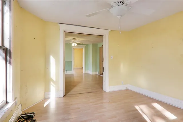 a view of a hallway with wooden floor and a bathroom