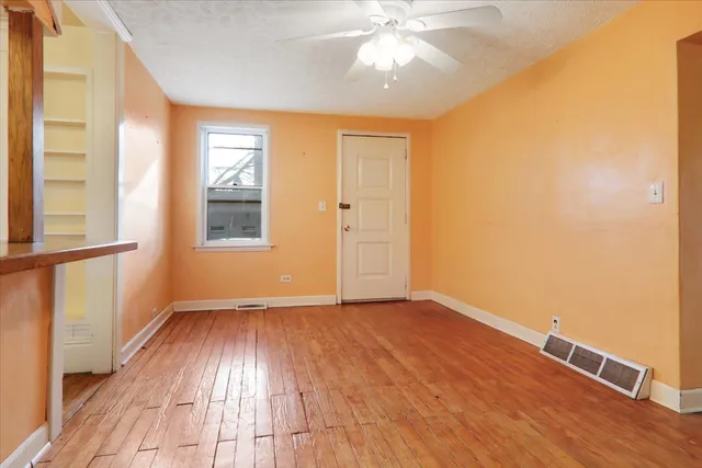 an empty room with wooden floor fan and windows