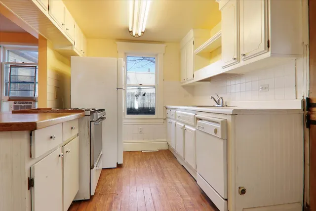 a kitchen with cabinets stainless steel appliances a sink and wooden floor