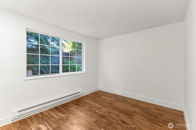 a view of an empty room with wooden floor and a window