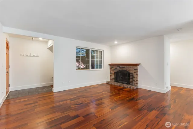 an empty room with wooden floor fireplace and windows