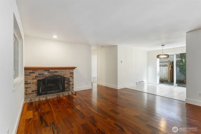 an empty room with wooden floor fireplace and windows