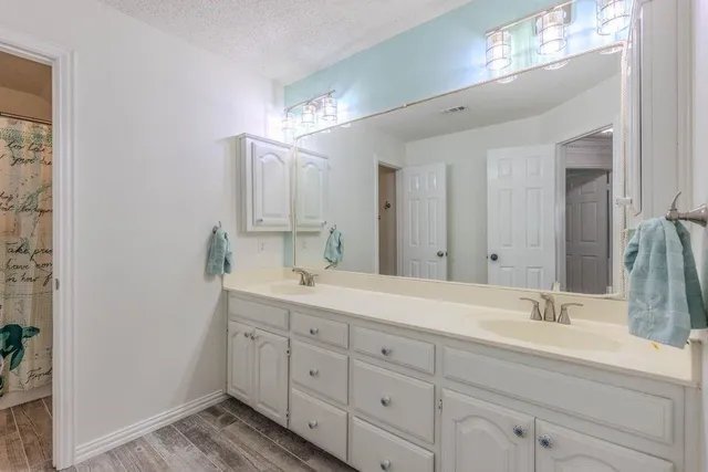 a spacious bathroom with double sink a mirror and a light fixture