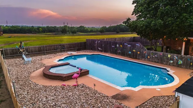 a view of swimming pool with a table and chairs under an umbrella