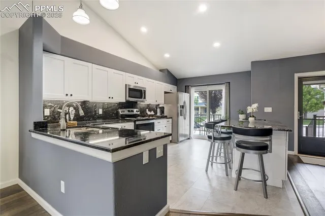 a kitchen with stainless steel appliances granite countertop a stove top oven a sink dishwasher a dining table and chairs with wooden floor