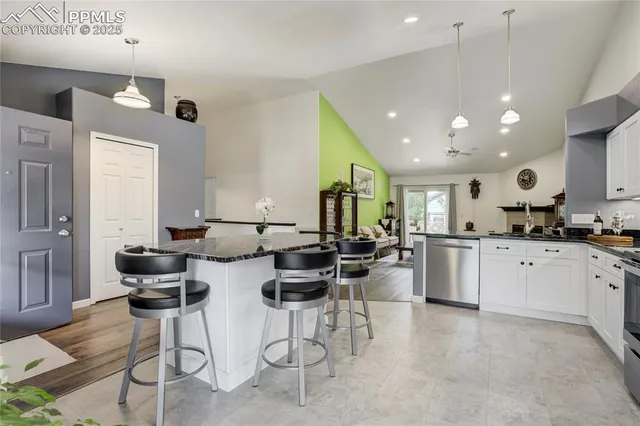 a kitchen with stainless steel appliances kitchen island granite countertop a stove a sink a dining table and chairs with wooden floor