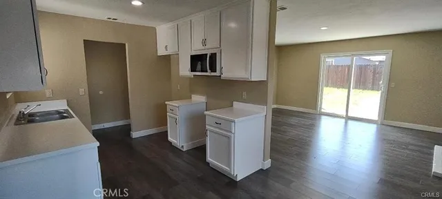 a kitchen with stainless steel appliances a stove a sink a microwave a refrigerator a cabinets and wooden floor