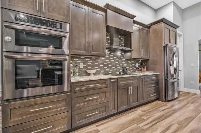 a kitchen with kitchen island granite countertop a stove a sink a dining table and chairs with wooden floor