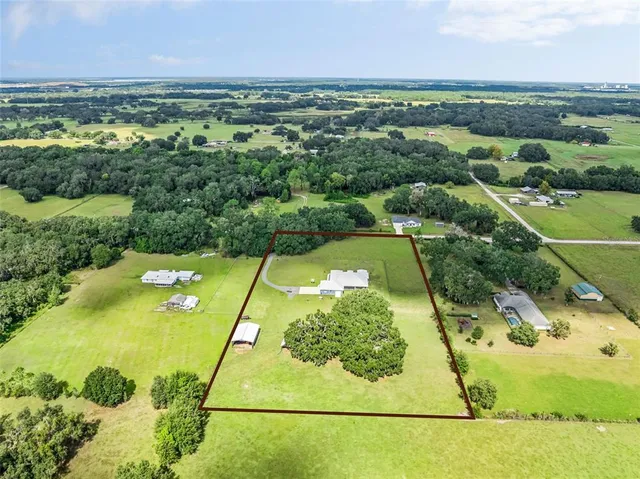 an aerial view of residential houses with outdoor space and trees