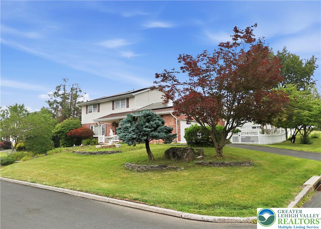 Well-maintained curb appeal offers a manicured lawn and mature landscaping with vibrant trees.