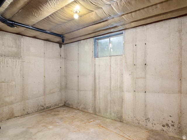 15680 North Beaver Dam Road Collinston, UT 84306 - Photo 37 of 49 Unfinished basement space featuring concrete block walls, a small horizontal window, and exposed ceiling insulation with visible piping