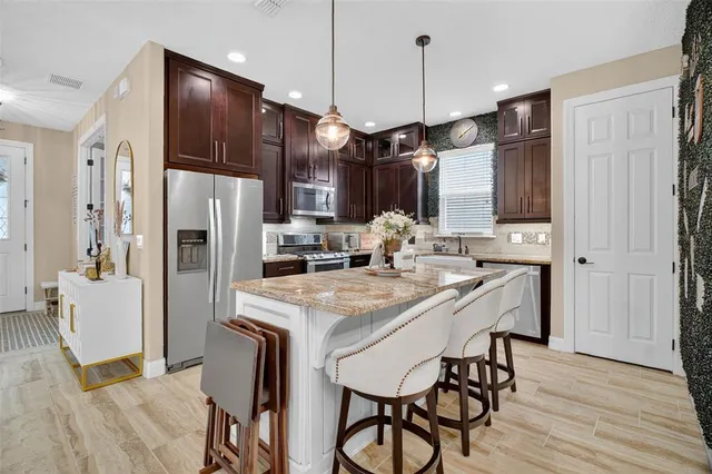 a kitchen with stainless steel appliances granite countertop hardwood floor sink stove and refrigerator