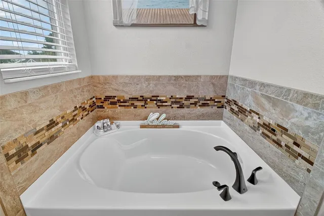 a bathroom with a granite countertop bathtub sink vanity mirror and toilet