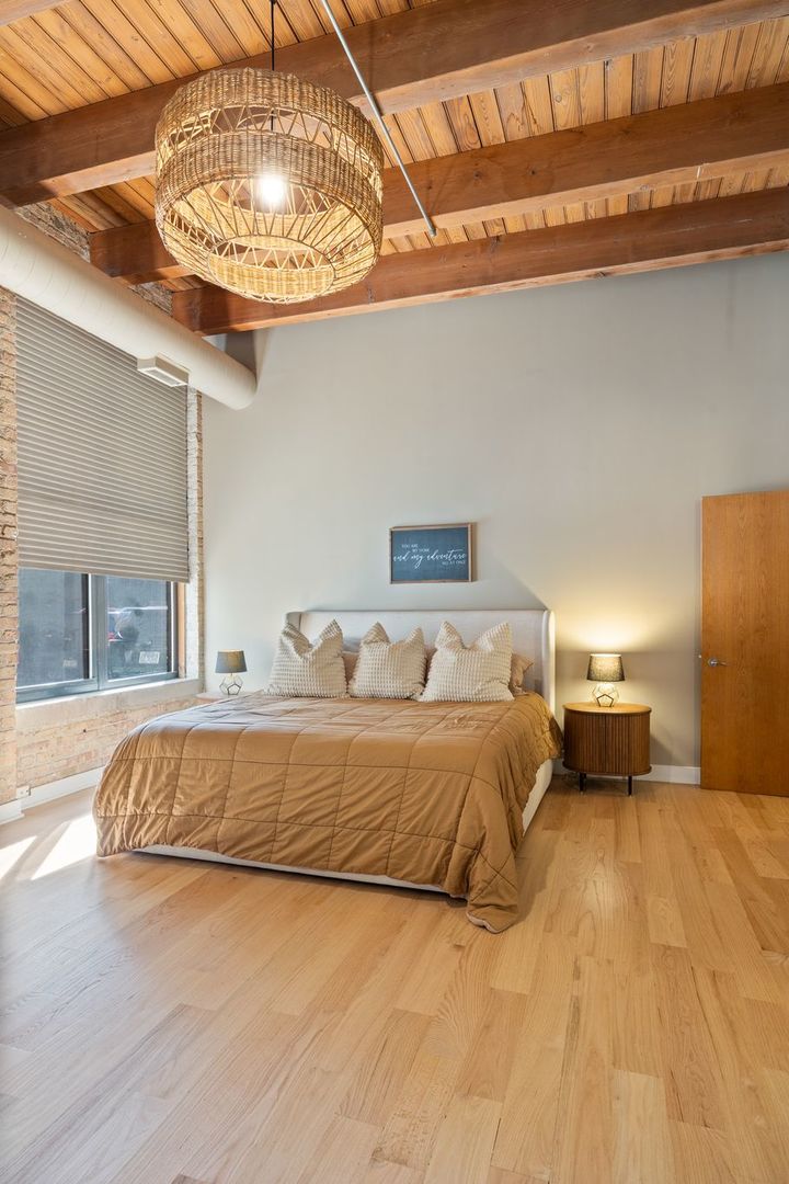 2222 North Racine Avenue, Unit 12 Chicago, IL 60614 - Photo 20 of 37 a bed sitting in a bedroom next to a chandelier