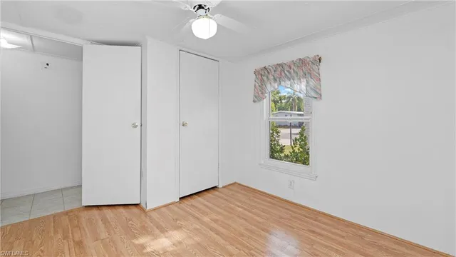 an empty room with wooden floor chandelier fan and windows