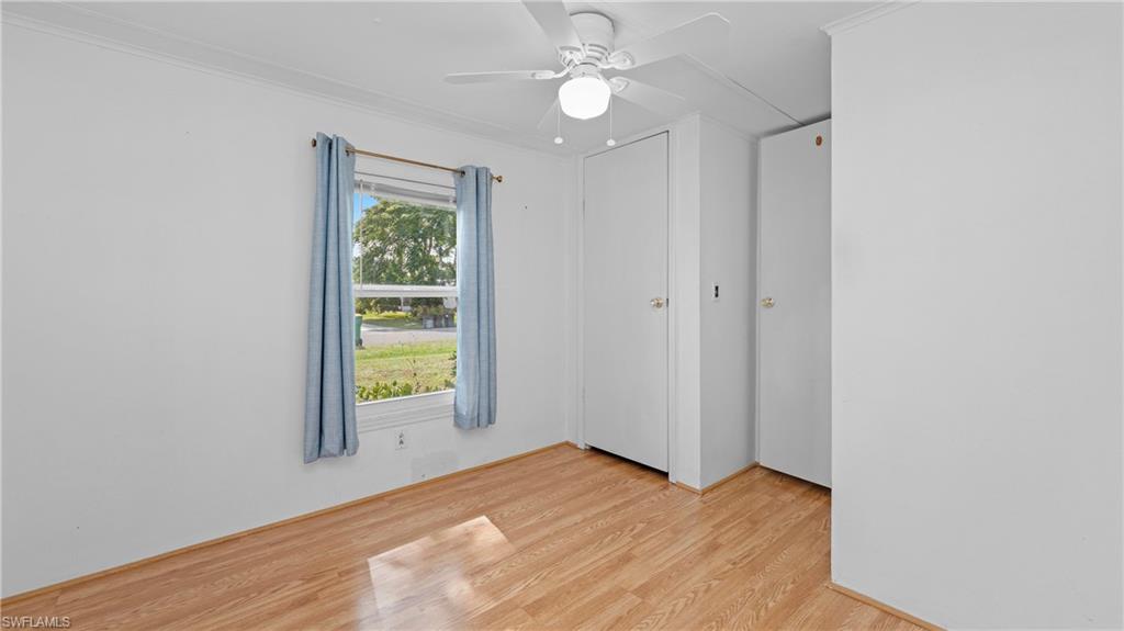 Undisclosed Address Naples, FL 34114 - Photo 12 of 20 an empty room with wooden floor chandelier fan and windows