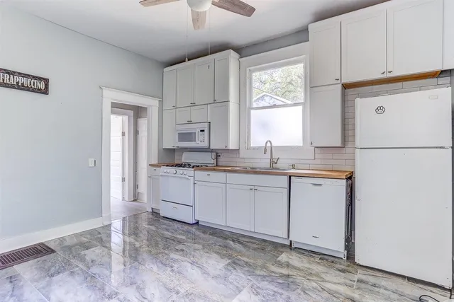 a kitchen with granite countertop white cabinets and white appliances