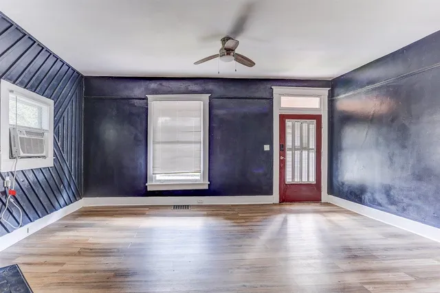 an empty room with wooden floor and windows