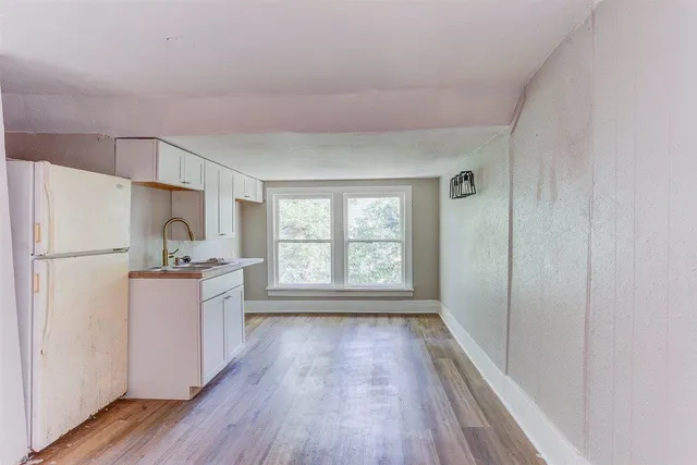 a kitchen with a refrigerator a sink and wooden floor
