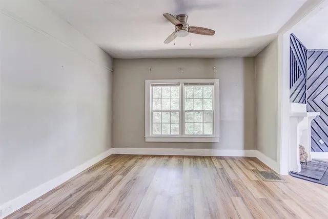 a view of an empty room with a window and wooden floor