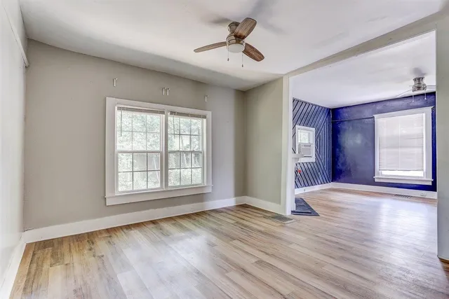 a view of an empty room with window and wooden floor